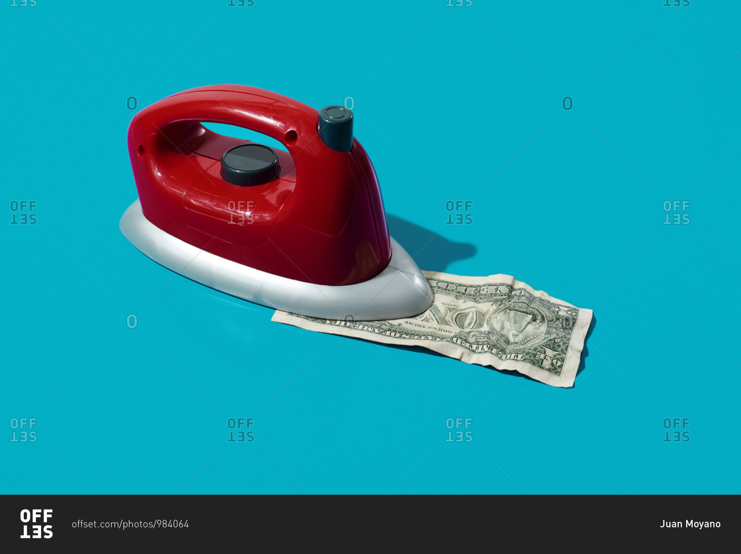 Ironing a dollar with a red iron on a blue background with some blank space