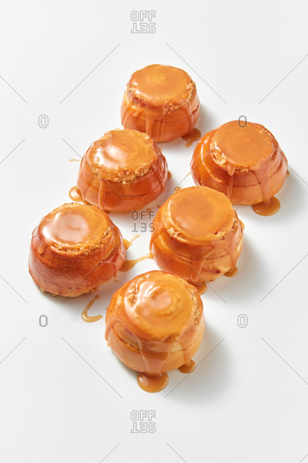 Freshly baked sweet delicious buns with caramel sauce, bakery pattern on a light grey background with soft shadows, copy space.