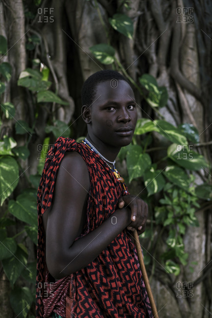 Maasai Man in traditional clothes standing in the forest