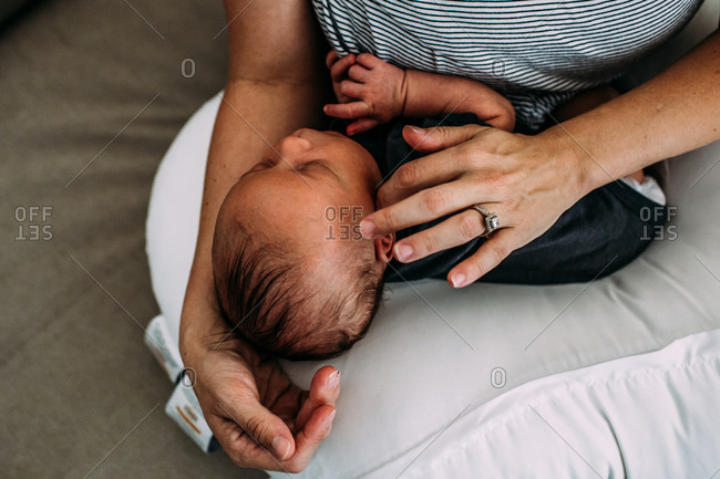 Overhead of newborn baby napping in mother's arms