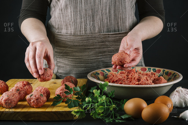 Female chef shapes minced meat to make homemade meatballs