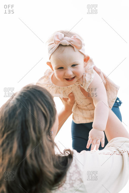 A cute one year old being held up by her mother.