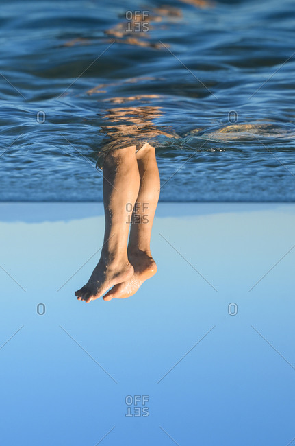 Young male legs coming out of the water. Surrealism