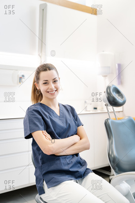 Young nurse in blue jacket smiles in the dental office before receiving