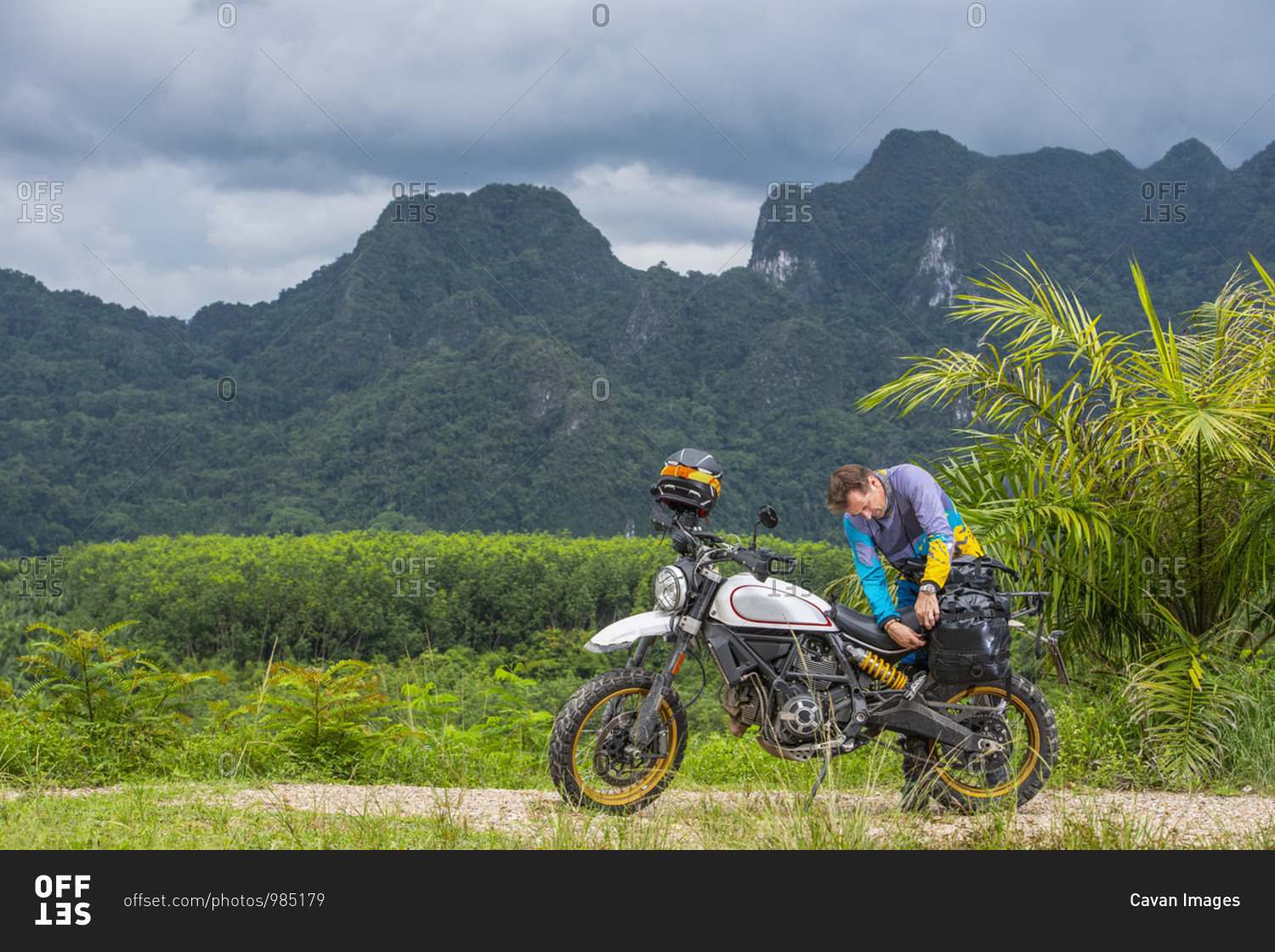 man packing his scrambler type motorcycle in the mountains of Thailand