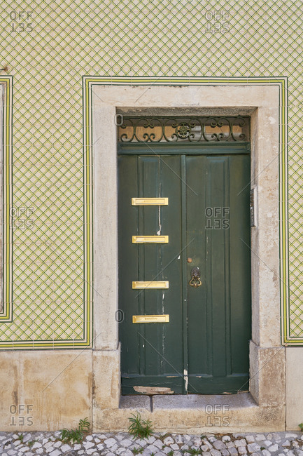 Green door surrounded by Moorish tile in the Lapa neighborhood, Lisbon, Portugal