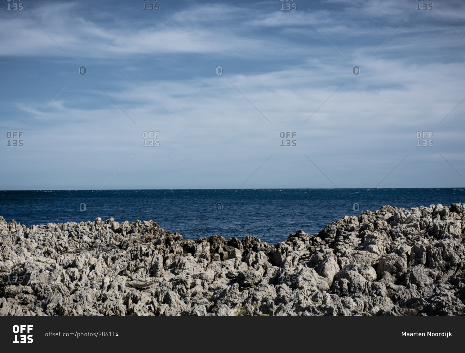 A sailing ship on the horizon of the Mediterranean Sea with a rocky coastline on the d\'Azur near Antibes in France.
