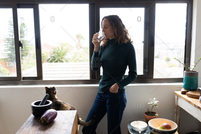 A Caucasian woman spending time at home, drinking water. Lifestyle at home isolating, social distancing in quarantine lockdown during coronavirus covid 19 pandemic.