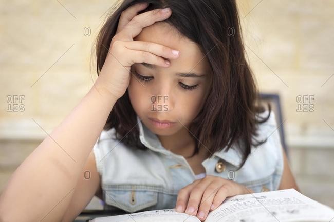 Close-up portrait of a girl sitting at a table reading a book