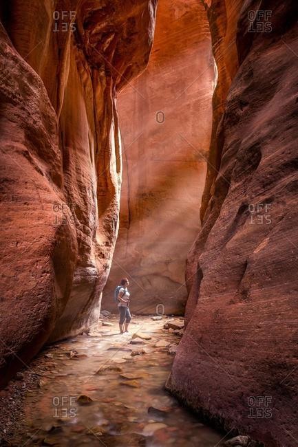 Woman standing in red slot canyon, Utah, United States