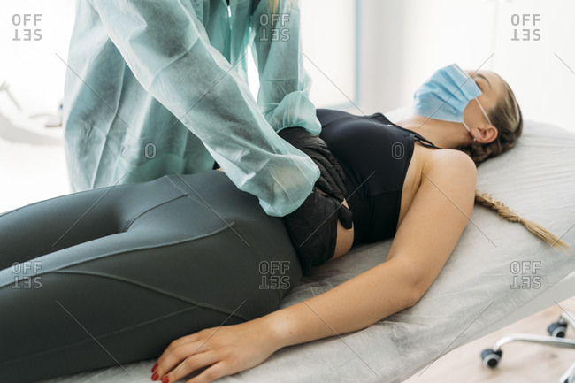 Doctor wearing protective clothes examining sportswoman