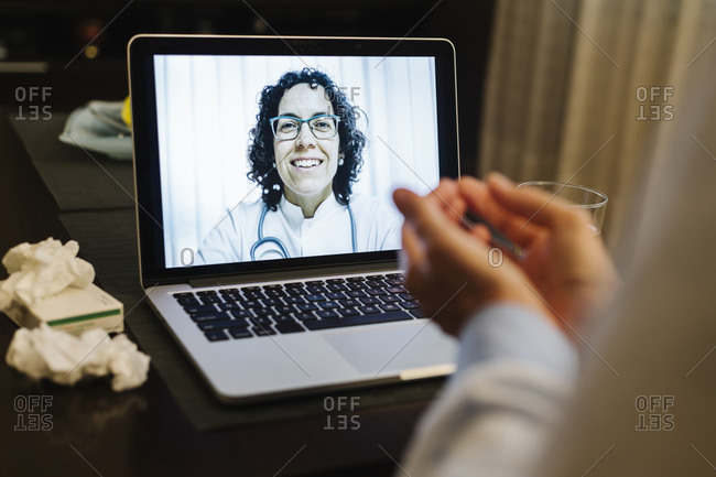 Retired senior ill woman discussing over video call with smiling doctor at home