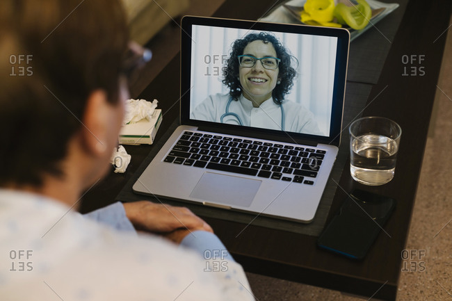 Smiling doctor on video call with ill senior woman through laptop