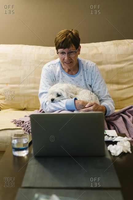 Ill elderly woman discussing over video call through laptop at home