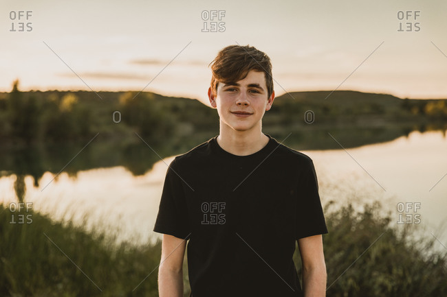 Teenage boy standing against swamp during sunset