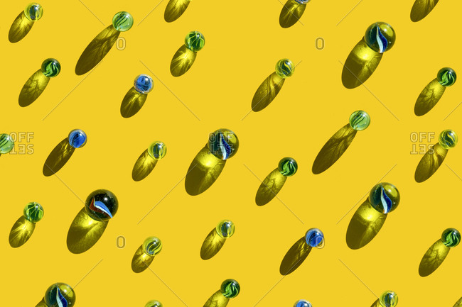 Pattern of blue and green marbles against yellow background