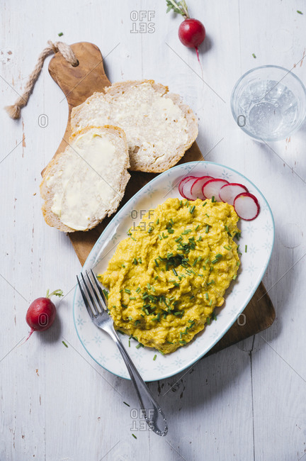 Plate of vegan scrambled eggs with chick-peas- chive- radish and bread