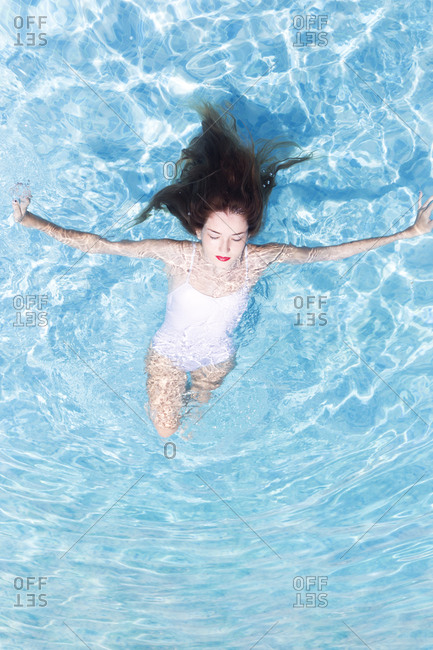 Young woman with eyed closed relaxing on swimming pool at resort during sunny day