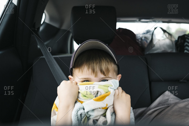 Close-up of cute boy peeking through towel while sitting in car