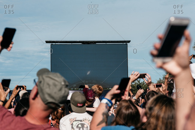 Brevard County, Florida - July 25, 2019: Spectators watch and record the Falcon 9 rocket launch with cell phones