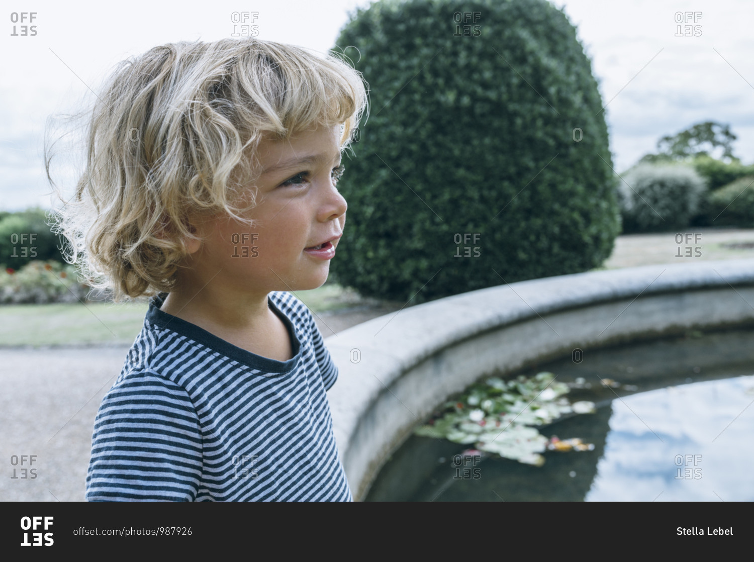 Portrait of tan blonde kid outside by a fountain