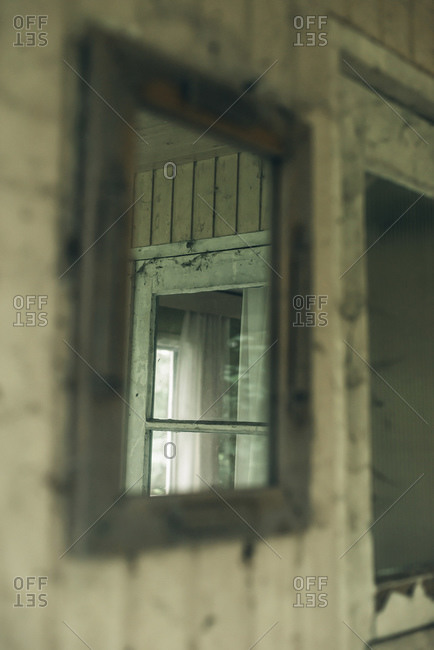 Old mirror on wooden wall next to front door of dilapidated home