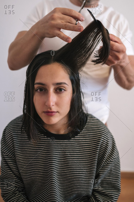 Father cutting hair of teenage daughter at home