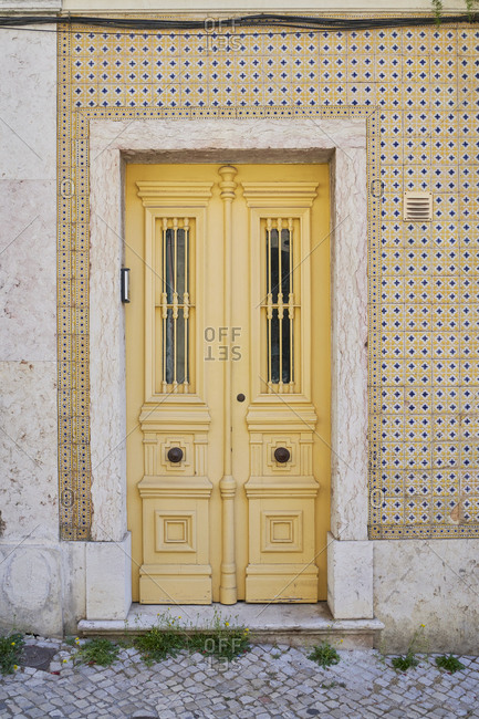 Yellow door surrounded by Moorish tile in the Lapa neighborhood, Lisbon, Portugal