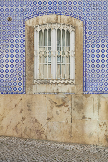 Window surrounded by bright blue Moorish tiles in the Lapa neighborhood, Lisbon, Portugal