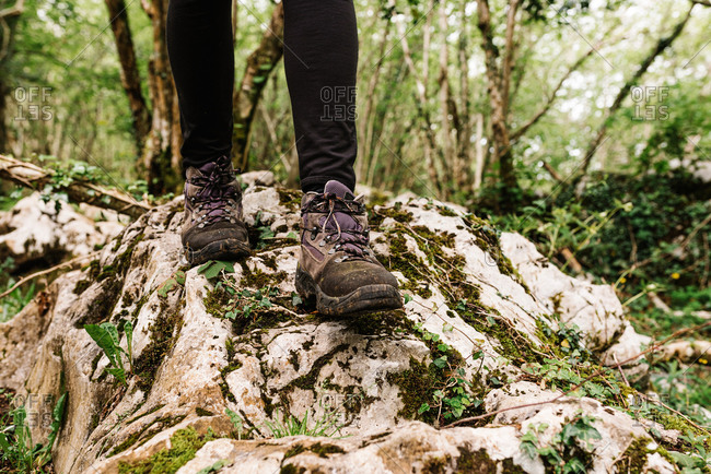 Faceless hiker in footwear for trekking standing on rough stone during vacation in forest in Asturias