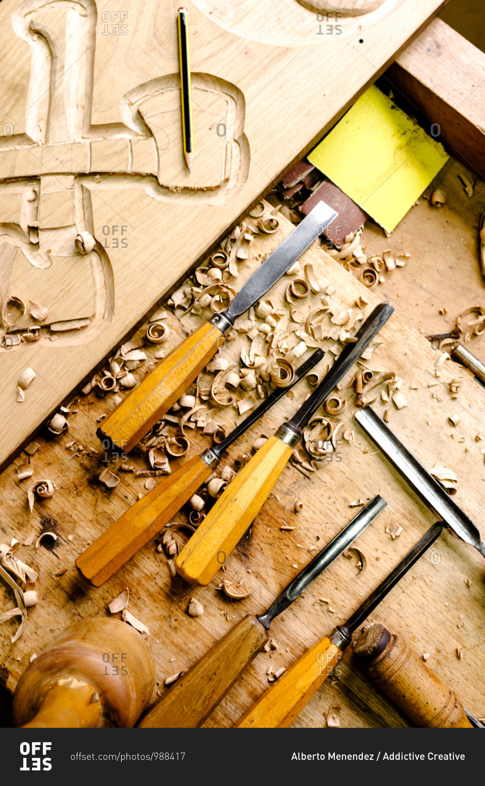 Top view of set of various chisels for wood carving placed on messy workbench with wood shavings