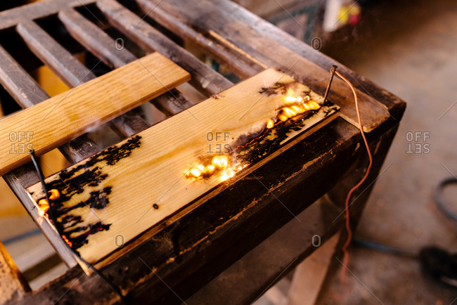 Closeup of electricity burning decorative pattern on wooden plank in carpentry workshop