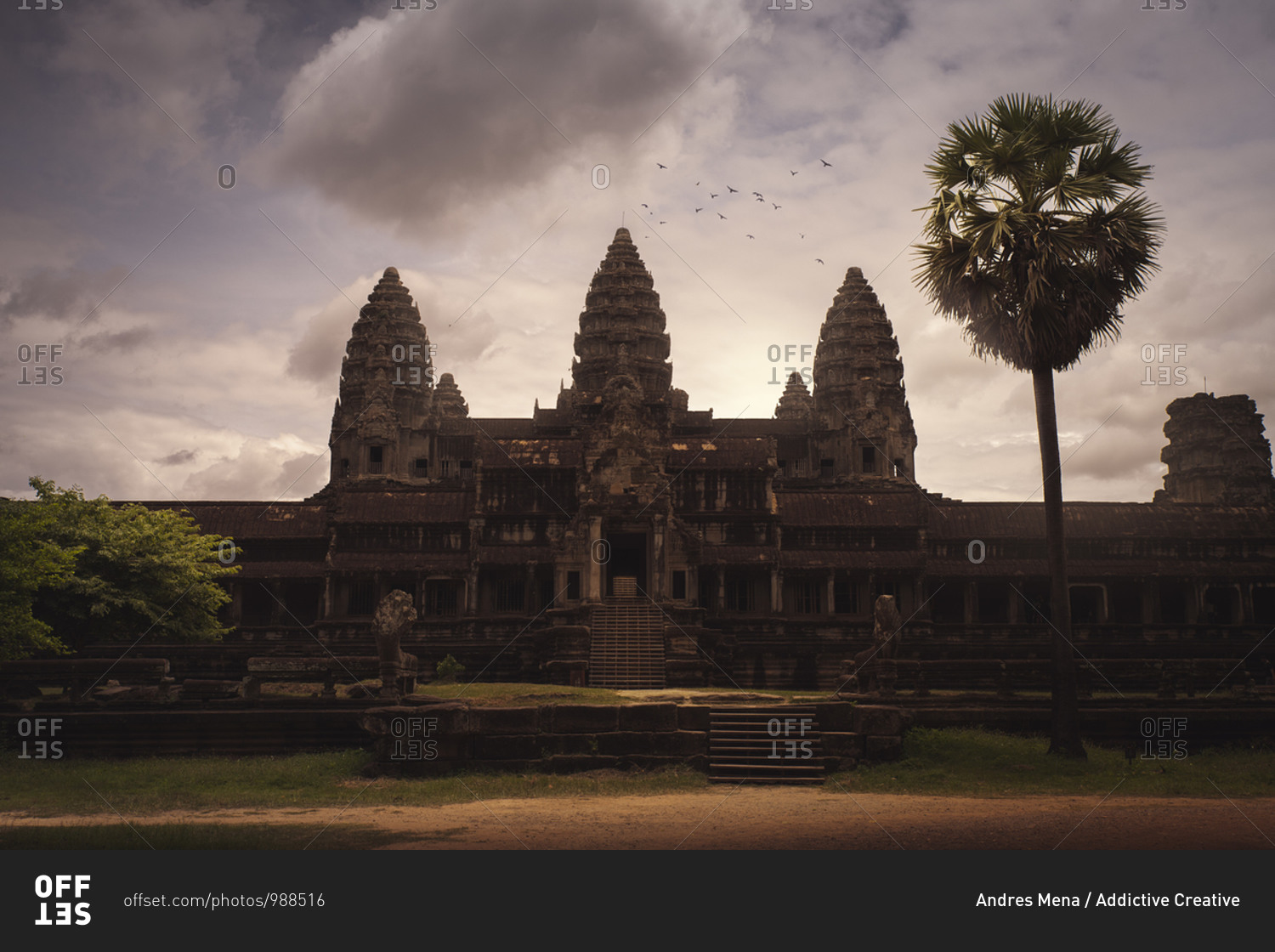 Stone oriental temple with shabby facade and towers on background of majestic sunset sky in Cambodia