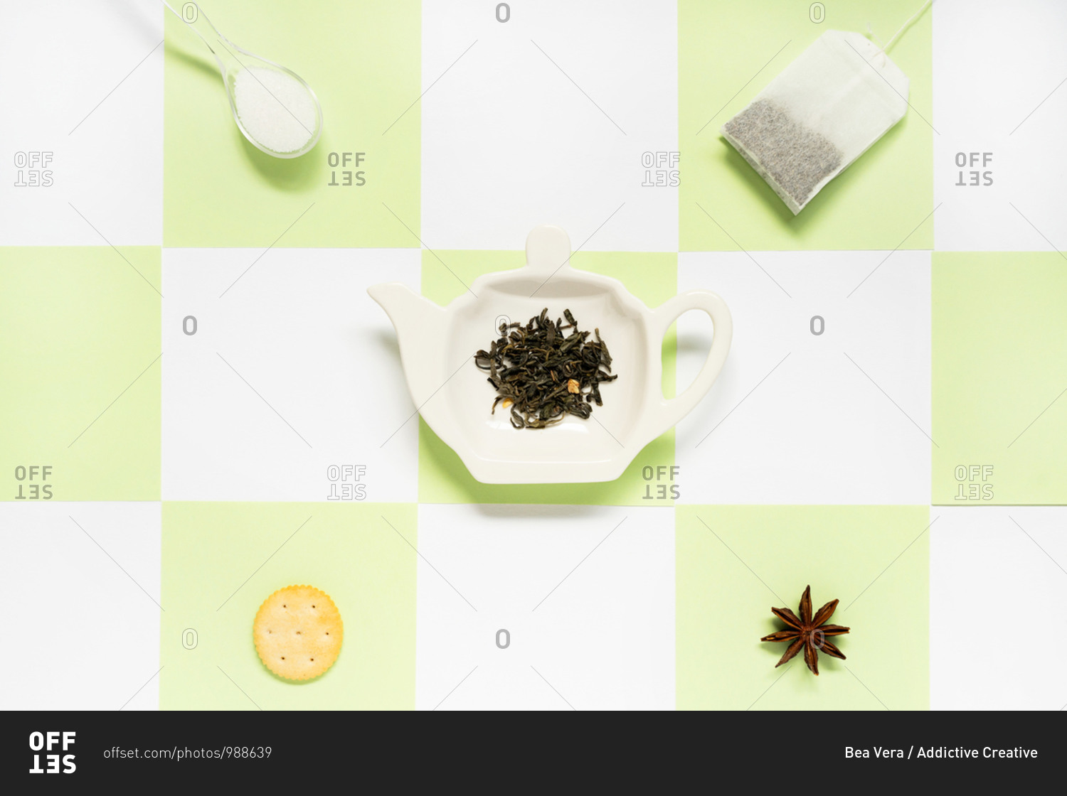 Top view of ceramic plate in form of teapot with green tea leaves near transparent tea bag with spoon of sugar and salty cracker with dry anise