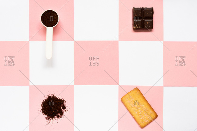 Top view of modern cellphone with empty screen surrounded by measuring spoon with cocoa powder and square cracker with piece of dark chocolate
