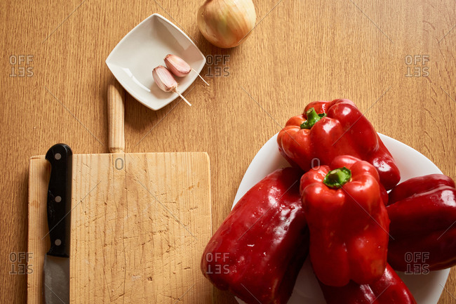 From above of wooden table with fresh red peppers placed near rice and condiments for cooking stuffed peppers
