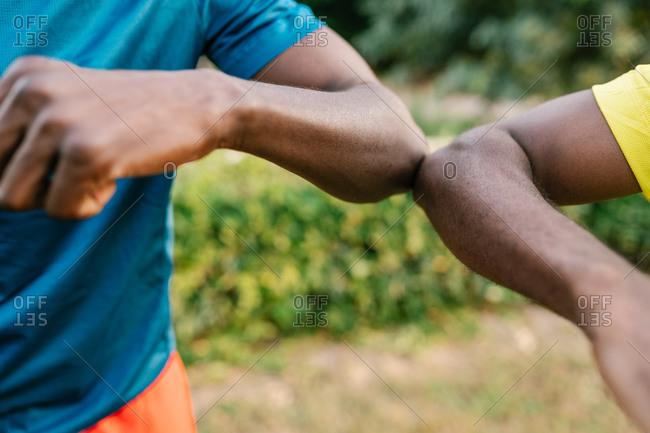 Close-up of two anonymous black men doing the elbow bump outdoors in the park