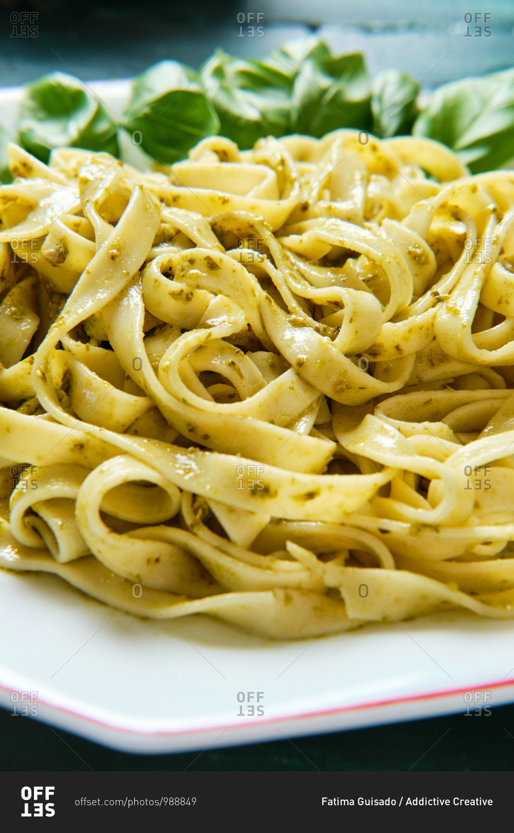 Side view of yummy tagliatelle with Italian pesto sauce with crunchy pine nuts and fresh basil leaves