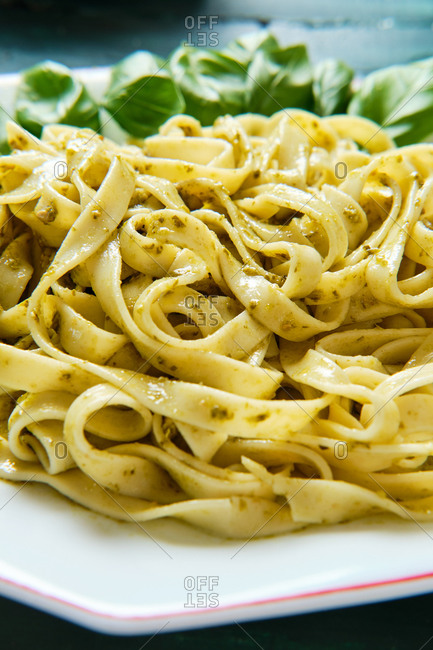 Side view of yummy tagliatelle with Italian pesto sauce with crunchy pine nuts and fresh basil leaves