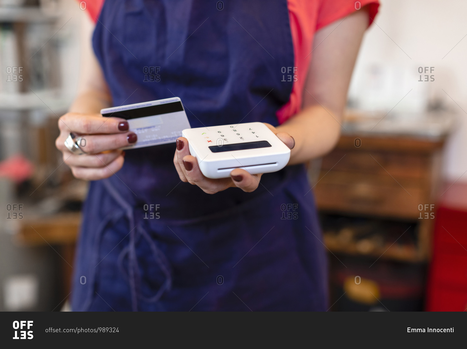 Unrecognizable female artisan with credit card and terminal taking payment during work in professional studio