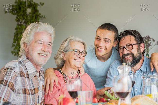Cheerful family having lunch together at home with teenager, father and grandparents