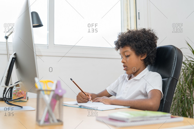 Afro american kid doing his home assignment in the living room