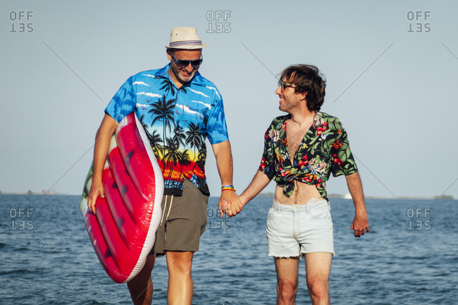Gay couple having fun on the beach with inflatable toy.
