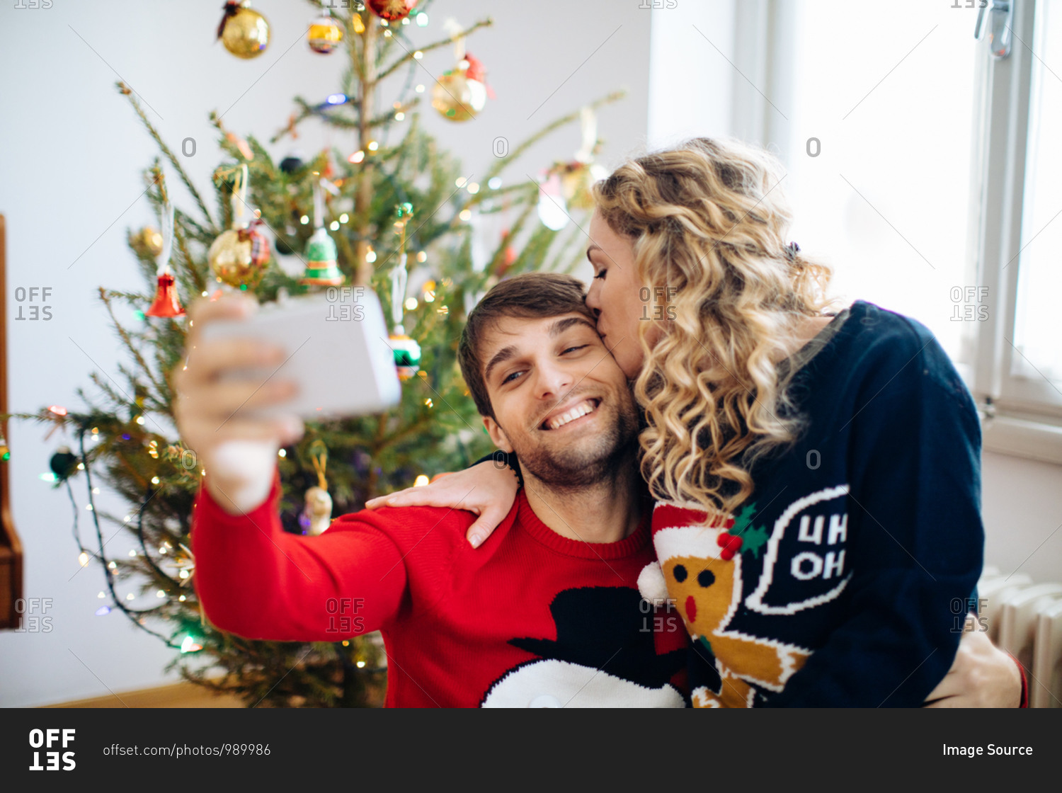Couple taking selfie in front of Christmas tree at home