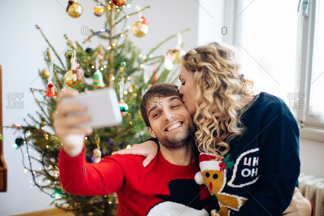 Couple taking selfie in front of Christmas tree at home