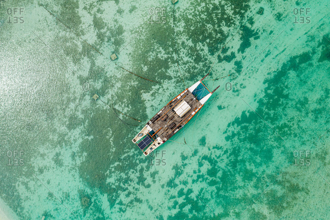 Aerial view of sailboat moored in shallow water.