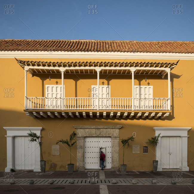 Old City, Cartagena, Bolivar Department, Colombia - January 3, 2020: Facade  of historic building in the Old City, painted walls, balcony and shuttered  windows and doors. stock photo - OFFSET