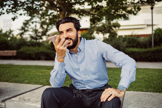 Portrait of bearded businessman wearing blue shirt, using mobile phone.