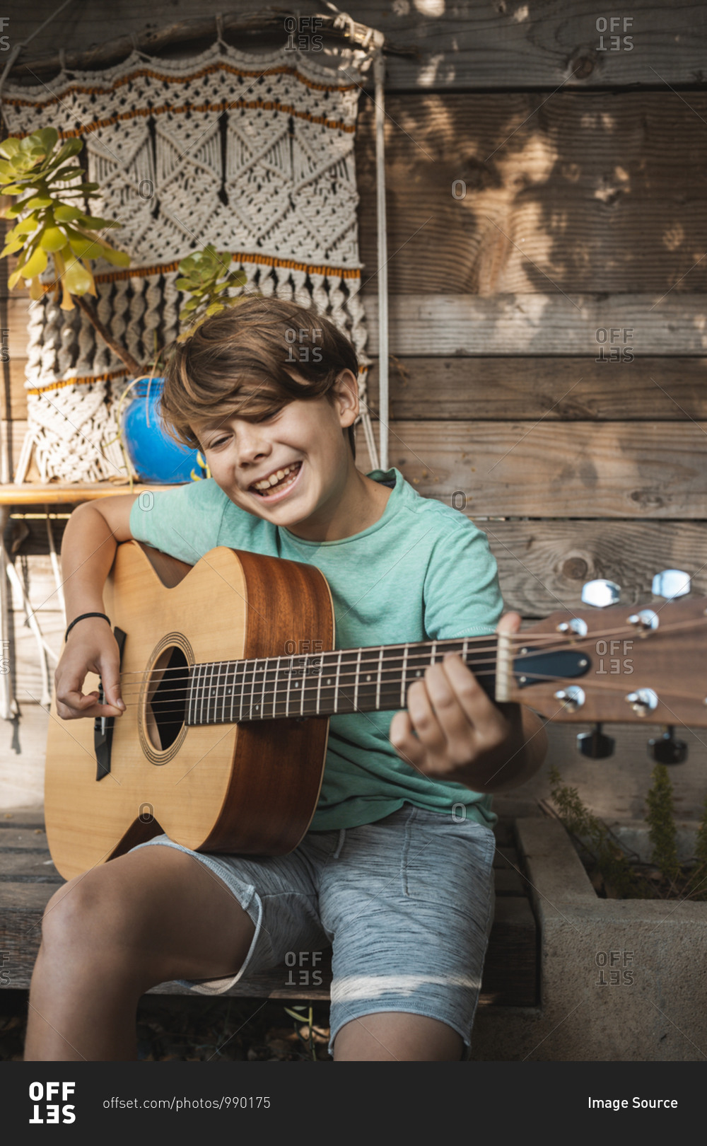 Portrait of brown haired boy playing guitar.