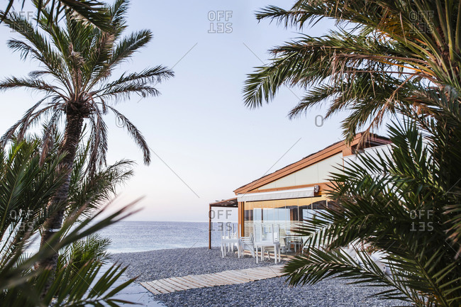 Spain- Granada- Almunecar- Beach restaurant with palms in foreground